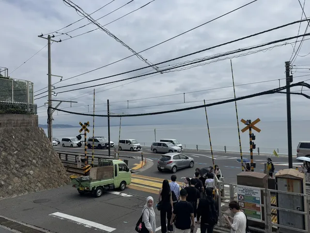 People walking over a railway crossing beside a coastal road, with the sea beyond