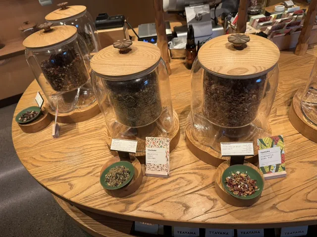 Glass jars of loose-leaf tea with tasting bowls on a round wooden table in a shop